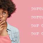 Pensive attractive curly African American female being deep in thoughts, raises eyebrows, curves lips, holds chin, wears fashionable clothes, stands against pink wall with the words Porque, Porqué, Por qué, Por que