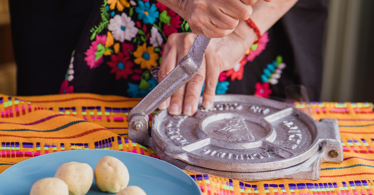 Mexican tortillas handmade: woman with traditional clothes pressing tortilla press in Mexico