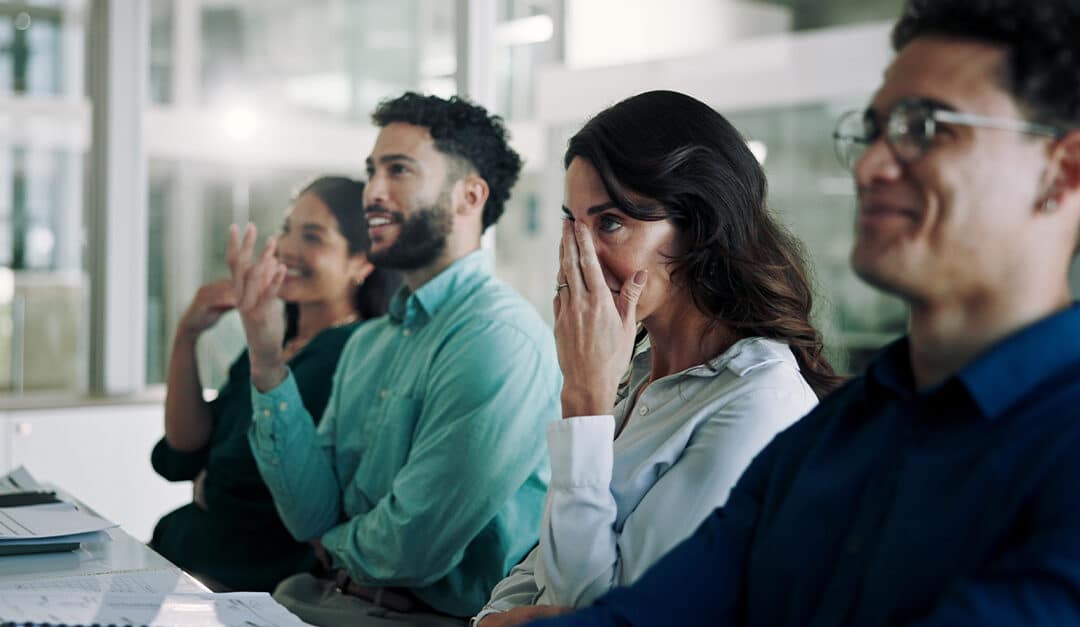 Business people in a meeting laughing and looking embarrassed, illustrating the blog topic "Funny and Embarrassing Mistakes People Make when Speaking Spanish"