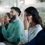 Business people in a meeting laughing and looking embarrassed, illustrating the blog topic "Funny and Embarrassing Mistakes People Make when Speaking Spanish"